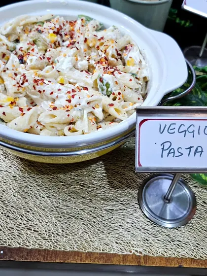A beautifully presented bowl of our Veggie Pasta in a creamy white sauce, sprinkled with chili flakes for a little kick. This dish was part of a stylish grazing table setup.