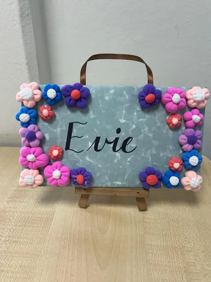 A close-up of Evie's beautiful nameplate, with a lovely colour palette of purples, pinks, and blues.