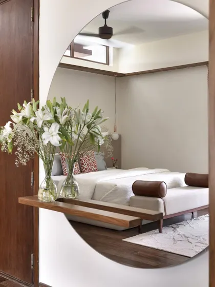 The large, backlit round mirror in the 'A Walk in the Clouds' primary room serves as a stunning focal point and a functional dresser, reflecting the serene and minimal design of the space.