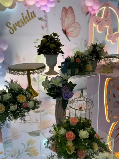 A close-up of the dessert table area, showing the floral arrangements and butterfly details.