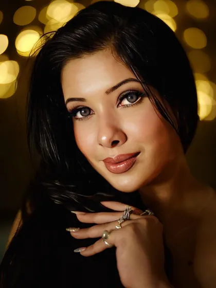 This close-up showcases a signature glam look with a soft focus background. The makeup features luminous skin, a defined brow, and glossy lips, creating an ethereal and captivating portrait.