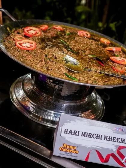 Our Hari Mirchi Kheema, a spicy and aromatic dish served from a live tawa station, garnished with fresh tomatoes.