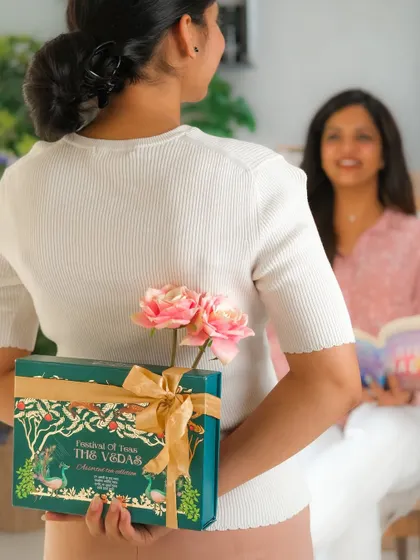 A daughter hiding a beautifully wrapped gift box behind her back to surprise her mother, telling a sweet, relatable story.
