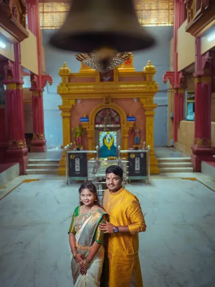 A creative shot of a South Indian couple in a temple, with the large temple bell blurred in the foreground. This adds a dynamic element and sense of place to the portrait.