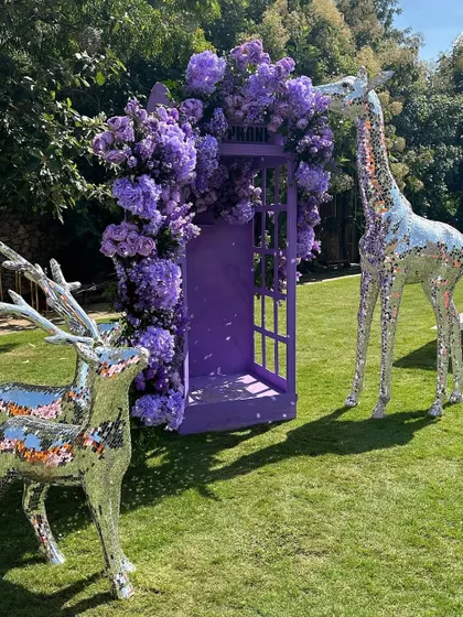Mirrored animal statues, like a deer and giraffe, add a touch of modern whimsy to this purple-themed outdoor event.