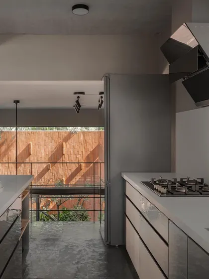 The kitchen is situated on a level above the car park, a design choice that allows it to remain connected to the main living volume and garden views. This galley-style kitchen is efficient and modern, with sleek cabinets and an open view.