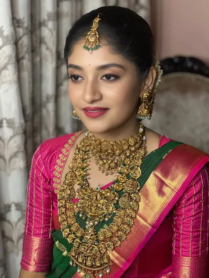 This look is a beautiful example of pairing makeup with jewel tones. The bold pink lip and soft brown eyes perfectly complement the bride's green and pink Kanjeevaram and antique gold jewelry.