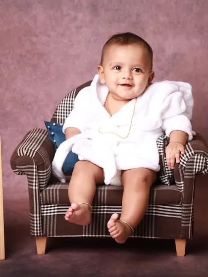 Celebrating the half-birthday milestone with a fun and quirky studio session. This little one is styled in a comfy robe on a miniature armchair, marking six months of growth and giggles.
