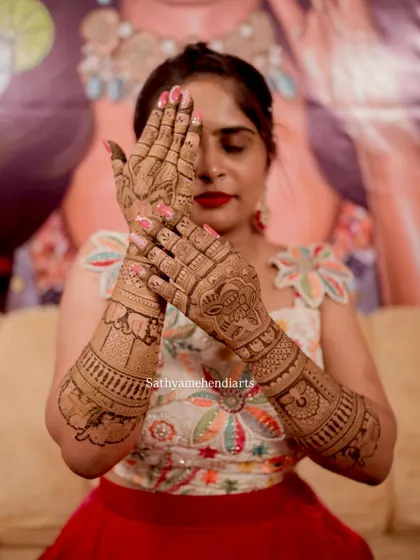 A beautiful pose showing off the intricate details of her wedding mehendi. The design covers her hands and forearms completely.
