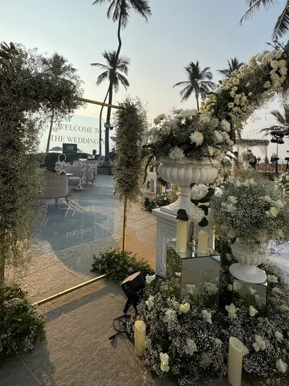 The welcome area for the white wedding, featuring a chic acrylic sign and lush floral arrangements, setting a tone of modern elegance from the very first moment.