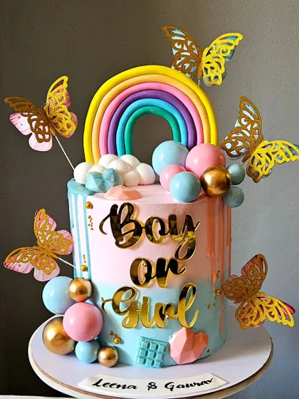 Another angle of the "Boy or Girl" gender reveal cake, showing the cascade of colorful spheres and the shimmering golden butterflies.