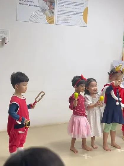Another shot of the children's Christmas performance, with educators guiding them. The joy on their faces is what these celebrations are all about.