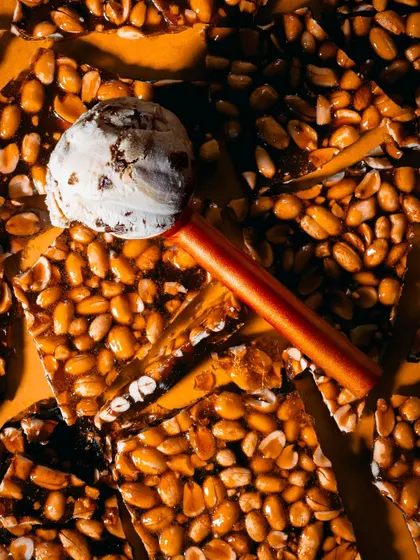 A creative flatlay featuring ice cream on a bed of chikki (peanut brittle). The textures and colors create a visually interesting composition that's both artistic and appetizing.