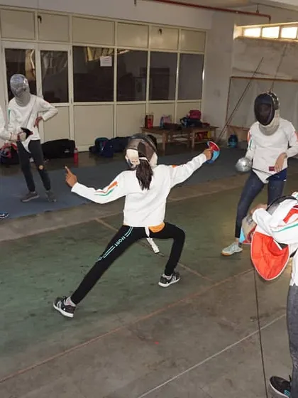 A student practices her lunge towards a partner during a footwork drill. This helps fencers gauge distance and timing for their attacks.