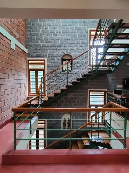 I love to let natural materials converse with each other. In this space, the cool grey of the stone wall, the warm red of the hollow clay blocks, and the rich tones of the wooden staircase create a balanced and harmonious interior.