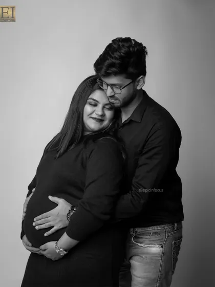 A gentle and intimate black and white portrait. The husband's embrace from behind provides a sense of safety and love.