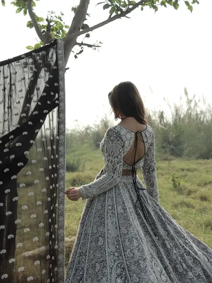 The back of this black and white lehenga features a daring deep-back blouse, adding a touch of modern allure to the traditional embroidery.