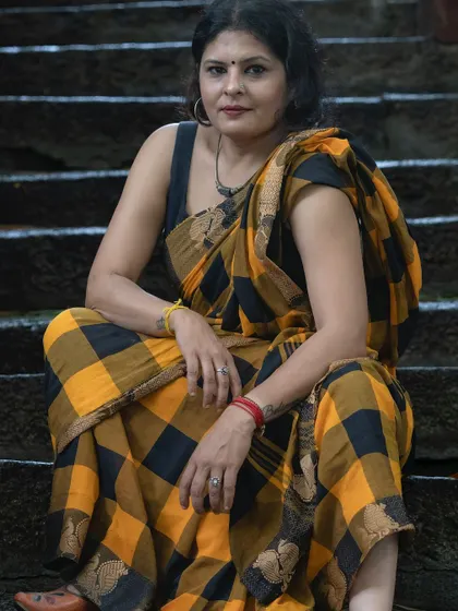 A seated pose in the checkered saree, showcasing a rugged and confident expression. My styling helps you explore different facets of your personality.