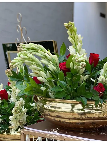 A beautiful arrangement of tuberoses and roses in a traditional brass bowl.