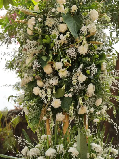 A lush, cascading arrangement of white flowers and green foliage, creating a dramatic and organic floral statement.