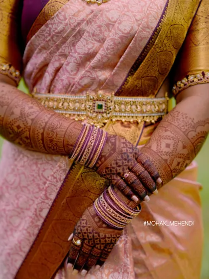 The deep color of the mehndi stain looks absolutely regal with the bride's traditional silk saree and gold jewelry. This is the beautiful result we always aim for.