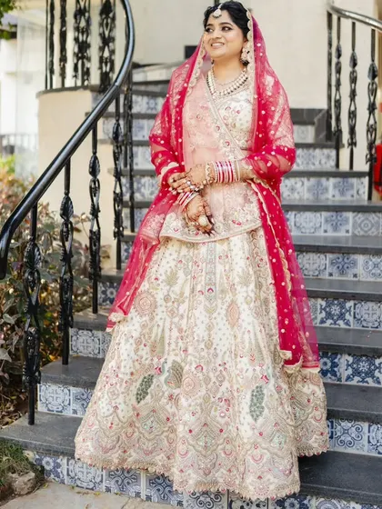The bride on the stairs, showcasing her full wedding look. The intricate hairstyle and flawless makeup complete her elegant ensemble.