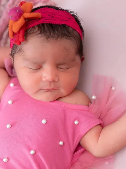 The face of an angel. This close-up from the unicorn session highlights the baby's sweet, sleeping face, adorned with a bright pink and orange headband.