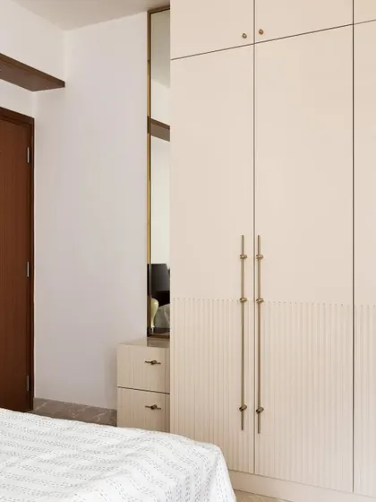 This guest room wardrobe features clean white shutters with elegant long handles and a lower section with a grooved texture, adding a subtle detail.
