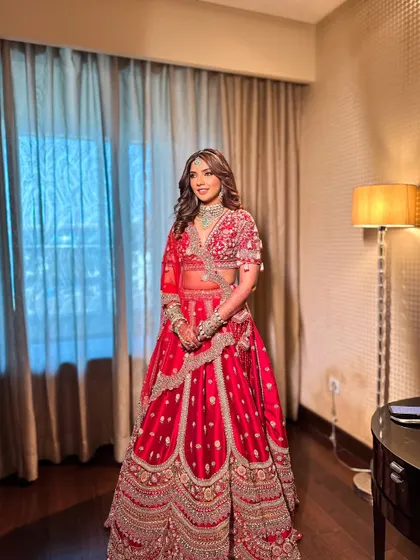 A full-length shot of Priyanka in her stunning red lehenga. The makeup was designed to complement her outfit, with a focus on radiant skin that looks beautiful in any light.