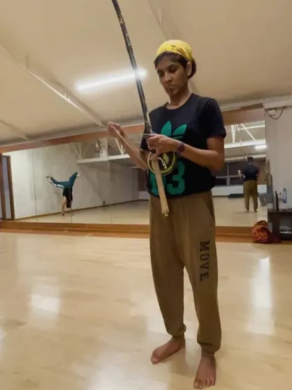 Another look at a student with a Berimbau. In the background, you can see the reflection of another student practicing an acrobatic move, showing how music and movement are always connected in our classes.