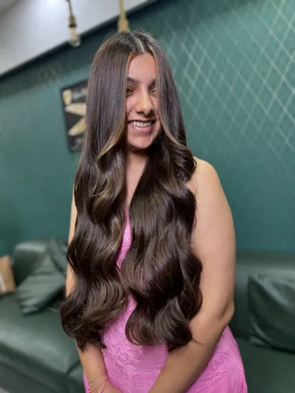 The ultimate goal for long hair: healthy, glossy, and full of life. This look features subtle face-framing highlights on a rich brown base, styled into soft, flowing waves that look effortlessly glamorous.