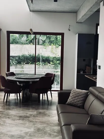 A cozy dining nook set against a large window that looks out onto a private green space, blurring the line between the interior and the garden.