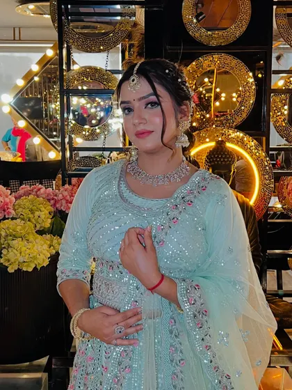 A lovely portrait showcasing a soft and pretty party look. The model is wearing a light blue sequined lehenga, with makeup featuring pink eyeshadow and a braided hairstyle.