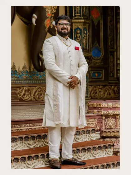 A classic portrait of the groom-to-be in a sophisticated off-white sherwani. His confident and happy demeanor is captured perfectly against an ornate backdrop.