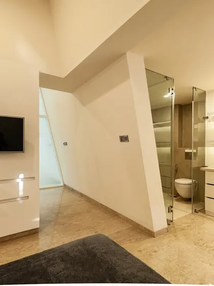A guest room where the angularity of the architecture defines the space. Built-in furniture and storage are integrated into the walls to maintain a minimalist aesthetic.