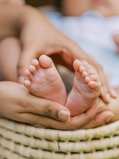 A close-up on the baby's feet being held in a parent's hands, a classic and timeless detail shot from a newborn session.