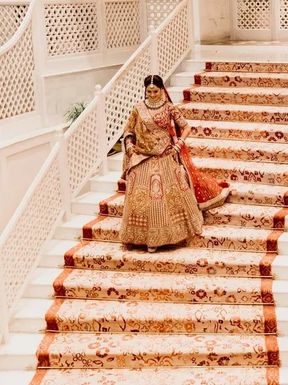 A grand staircase shot of the bride descending, her beautiful lehenga trailing behind her. A classic and elegant bridal portrait.