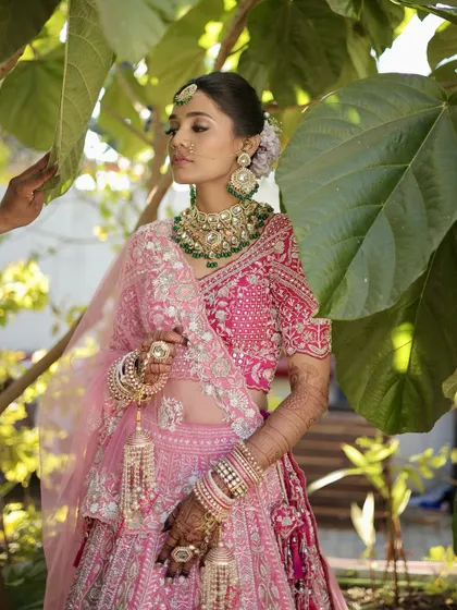 A beautiful outdoor shot where the natural light enhances the makeup. The pink tones in her lehenga are echoed in the soft blush and lip color.