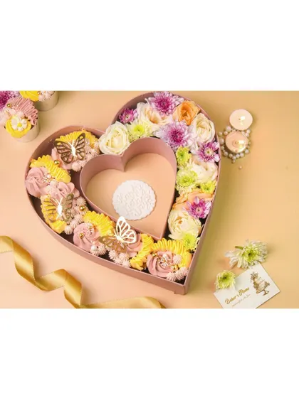 A large, heart-shaped bakery box filled with cupcakes and flowers. This is a very impressive and aspirational shot, perfect for Valentine's Day or anniversary promotions.