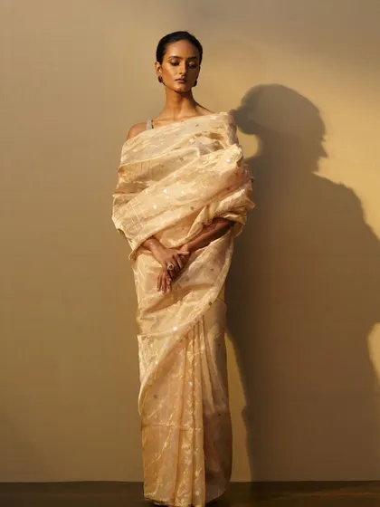 The full drape of the gold tissue saree, showing its sheer, lightweight quality. This is a beautiful addition to a bride's trousseau for post-wedding events.