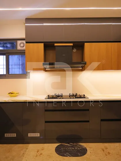 A spacious U-shaped kitchen with dark grey and wood cabinets. The clean lines, handleless drawers, and layered lighting create a sleek, contemporary, and highly functional cooking environment.