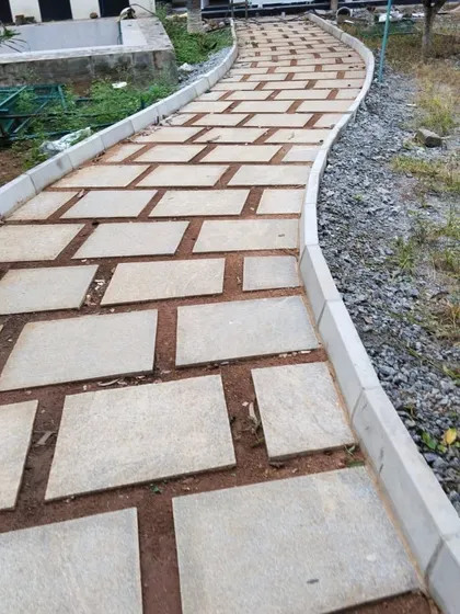 A wide, curving path made of rectangular stone pavers, designed to handle foot traffic in a large outdoor area. The precision in laying the stones ensures a stable and long-lasting surface.
