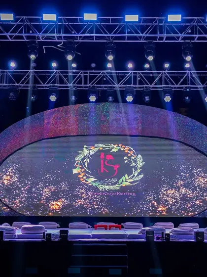 The main stage with a large, curved LED screen displaying the couple's wedding logo. This allows for dynamic and customizable backdrops throughout the sangeet performances.
