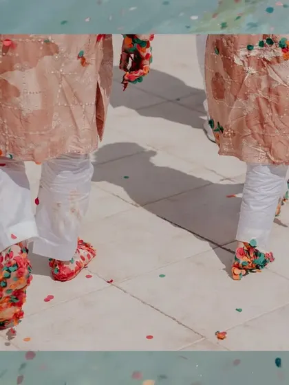 A creative shot of the couple's feet covered in colorful confetti after their haldi, set against a water texture, hinting at their post-ceremony ocean dip.