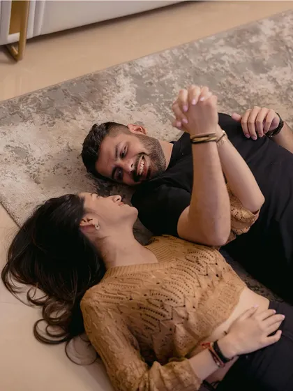 Lying together, sharing a laugh. This overhead shot captures a moment of pure, uninhibited joy and connection during their indoor couple shoot.