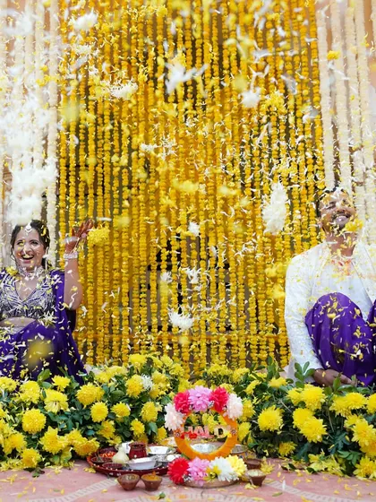 A playful flower fight between the couple during their Haldi, set against a backdrop of marigolds. This is the kind of candid, colorful fun we love to document.