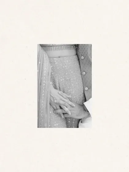 A minimalist, black and white detail shot of a couple holding hands.