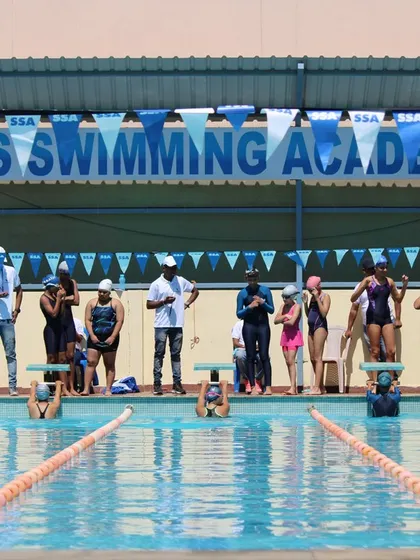 Swimmers on the starting blocks, focused and ready for the whistle at the Sasthapools Swimming Academy competition.