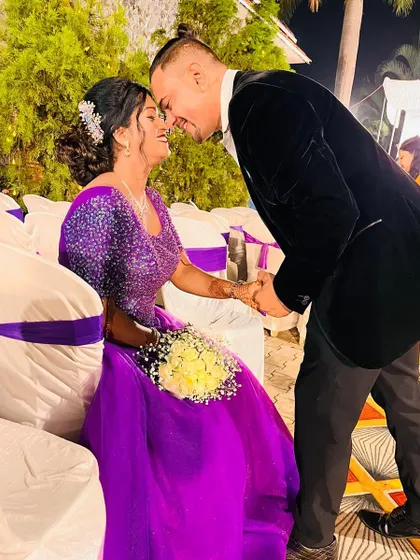 A true Cinderella moment. The bride looks radiant in this vibrant purple ball gown, sharing an intimate and joyful moment with her partner.