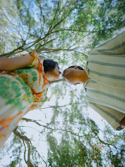 A creative, low-angle shot from a pre-wedding shoot in Mussoorie, capturing a playful kiss beneath a canopy of trees. I always look for unique perspectives to make your film stand out.
